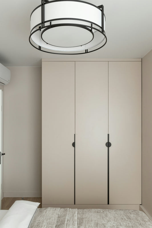 Modern beige wardrobe with black handles and round light.