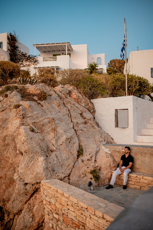 Man on stone ledge with greek white buildings