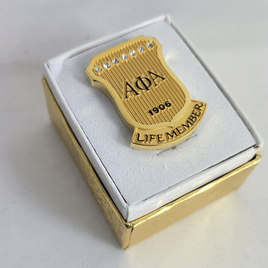 Alpha Phi Alpha gold Life Member lapel pin with 1906 shield and seven stones in gift box.