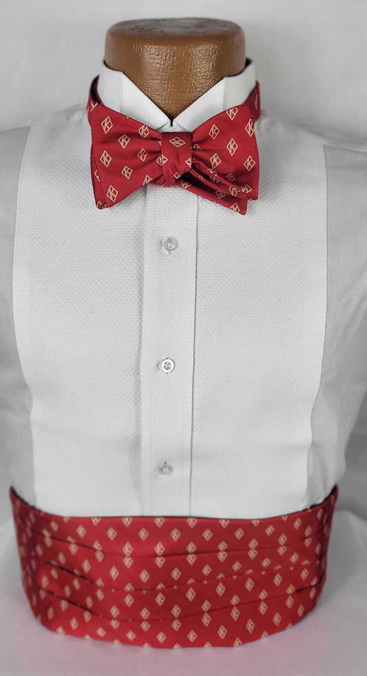 Formal men's attire featuring a white tuxedo shirt paired with a red bow tie and matching cummerbund, both adorned with a subtle diamond pattern, displayed on a mannequin against a white background.
