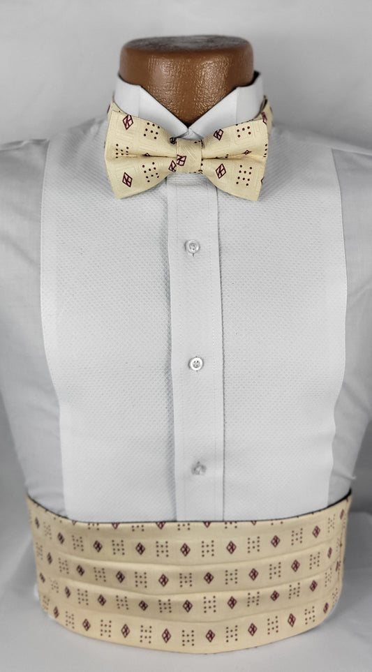 A formal men's outfit displayed on a mannequin, featuring a white tuxedo shirt paired with a light beige/cream cummerbund and bow tie set. Both accessories showcase a distinctive dark red/maroon diamond and dot pattern, adding a touch of elegance to the ensemble.